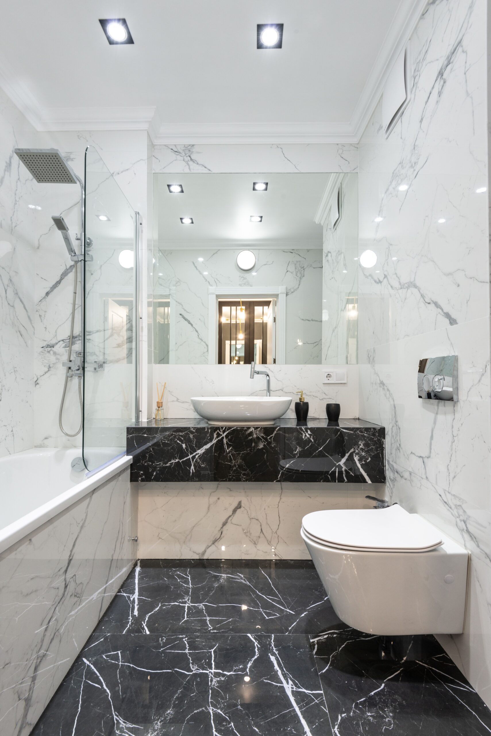 Black and white marble bathroom with bathtub, glass shower screen, floating vanity and wall-hung toilet