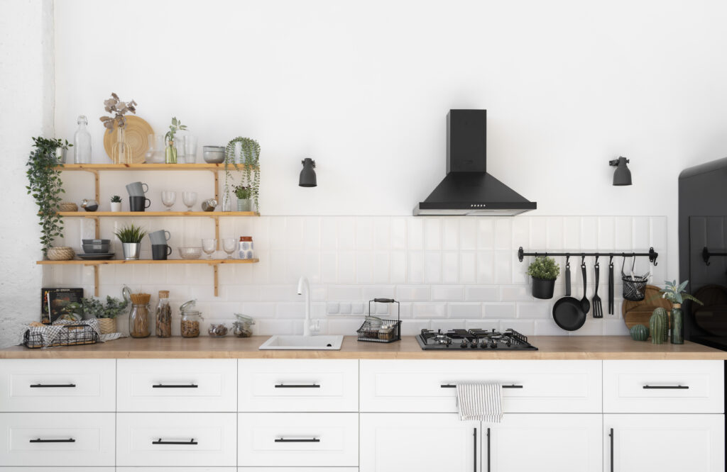 Bright kitchen with white cabinets, wood countertop, open wood shelves and black range hood